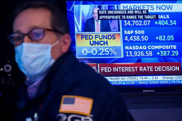 Na obrazovke je zobrazenie oznámenia o sadzbách Fedu, keď špecializovaný obchodník pracuje na svojom mieste na podlahe New York Stock Exchange (NYSE) v New Yorku, USA, 26. januára 2022. REUTERS/Brendan McDermid
