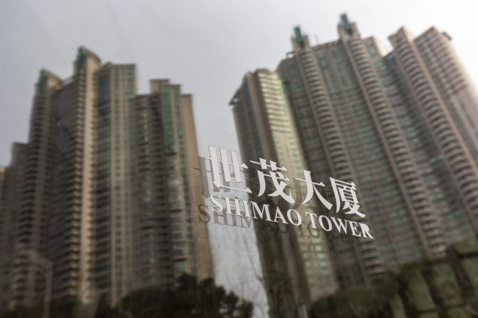 Obrázky rezidenčného majetku Riviera Garden, ktorý vyvinula spoločnosť Shimao Group Holdings Ltd., sa odrážajú na sklenenom paneli v blízkosti veže Shimao Tower, ktorú tiež vyvinula spoločnosť v Šanghaji v Číne v sobotu 8. januára 2022. Shimao, ktorý je dôvodom finančnej nákazy v čínskom realitnom priemysle, utrpel vo štvrtok najväčší výpadok dlhopisov po tom, ako veriteľ uviedol, že jedna z developerských jednotiek zlyhala na miestnom úvere. Fotograf: Qilai Shen/Bloomberg