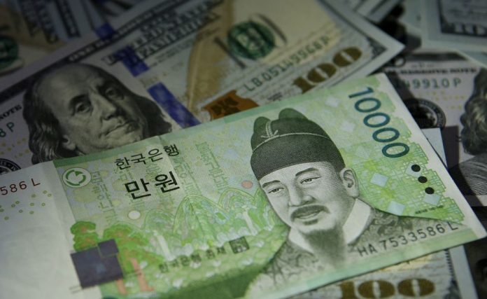 FOTO - Juhokórejská bankovka v hodnote 10 000 wonov je zobrazená na amerických 100-dolárových bankovkách na ilustračnej snímke z 15. decembra 2015 v Soule v Južnej Kórei. REUTERS/Kim Hong-Ji/File Photo