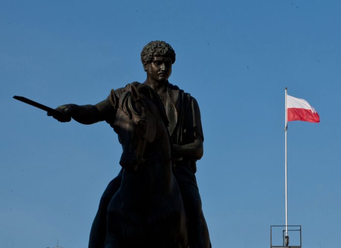 Poľská štátna vlajka vlaje nad sochou kráľa Stanislava Poniatowského vo Varšave, Poľsko; Zdroj: Piotr Malecki/Bloomberg