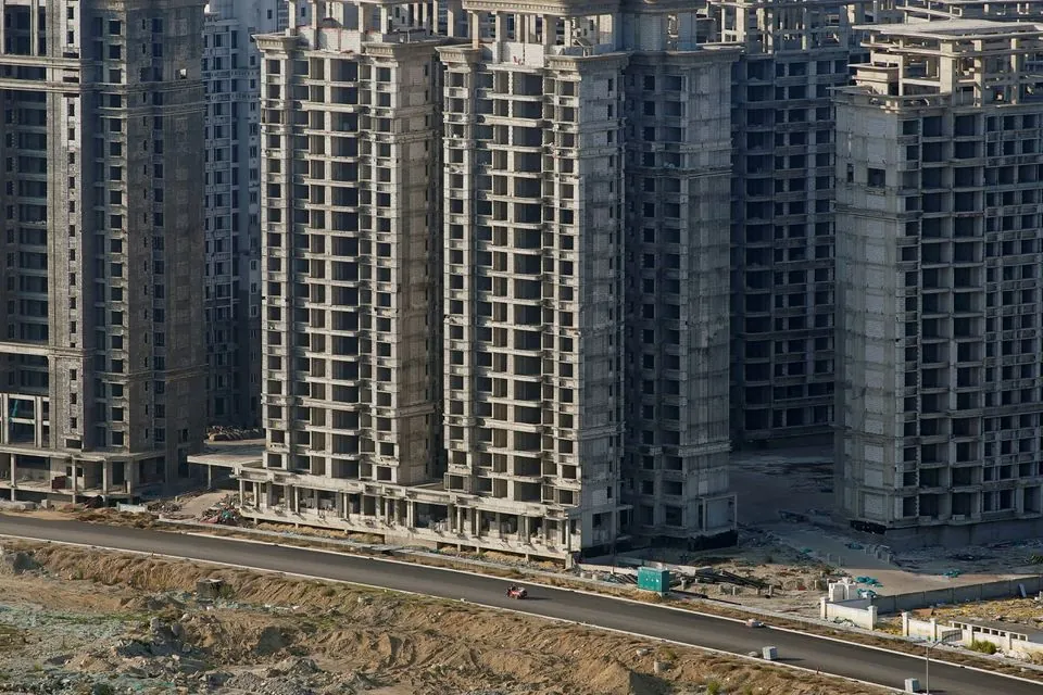 Vozidlo prechádza okolo niektorých z 39 budov postavených spoločnosťou China Evergrande Group, pre ktoré úrady vydali príkaz na demoláciu na umelo vytvorenom ostrove Ocean Flower Island v Danzhou, provincia Hainan, Čína 6. januára 2022. REUTERS/Aly Song/File Photo